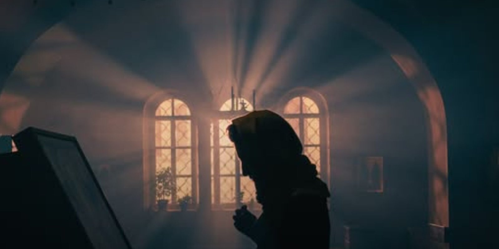 Pessoa em oração no interior de uma igreja, iluminada pela luz das janelas.